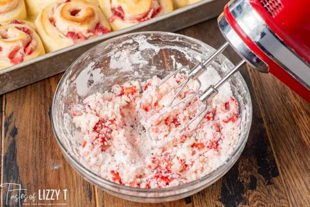mixing strawberry frosting for sweet rolls