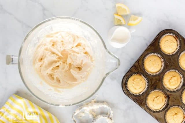 frosting in a mixing bowl and a pan of cupcakes