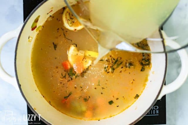 pouring chicken broth into a saucepan