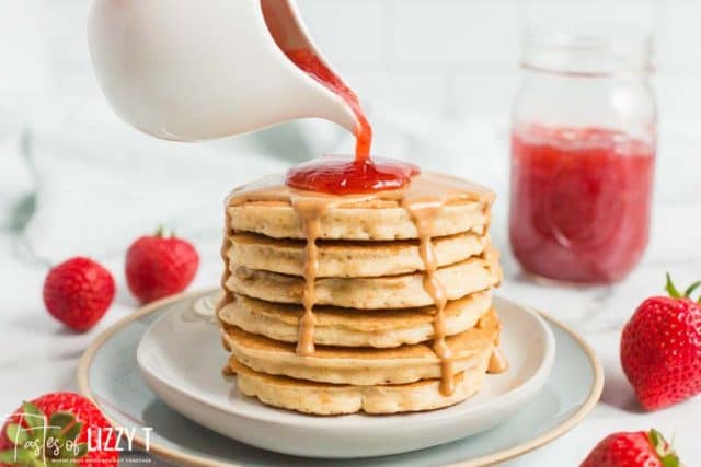 pouring jelly on a stack of peanut butter pancakes