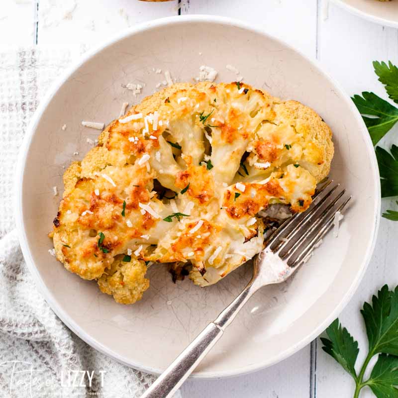 roasted cauliflower steak on a plate with a fork