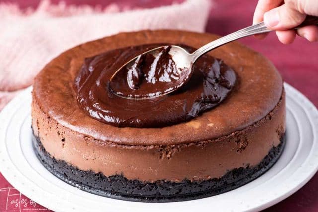 spooning chocolate ganache on a cheesecake