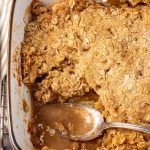 apple crisp in a baking pan with a spoonful out