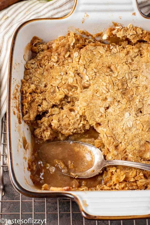 apple crisp in a baking pan with a spoonful out