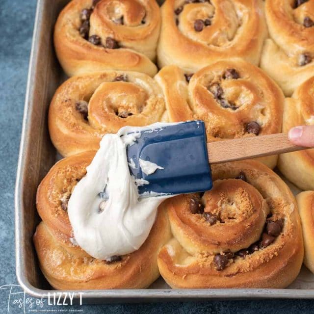 spreading marshmallow frosting on a roll