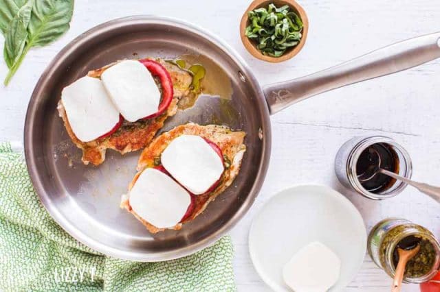 chicken in a skillet with tomato and mozzarella