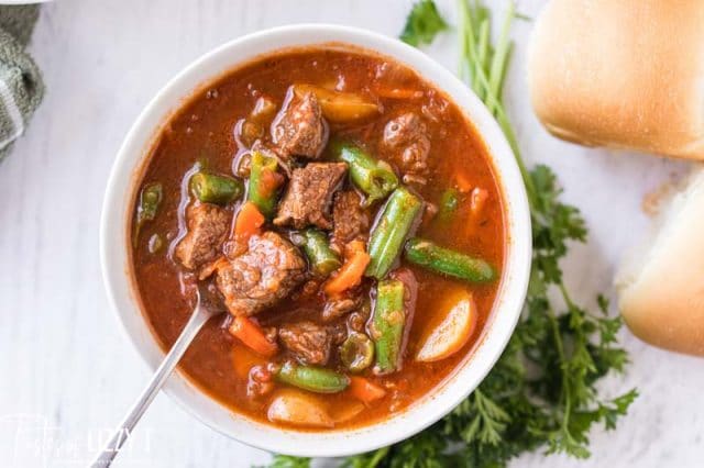 overhead view of beef soup in a bowl with spoon