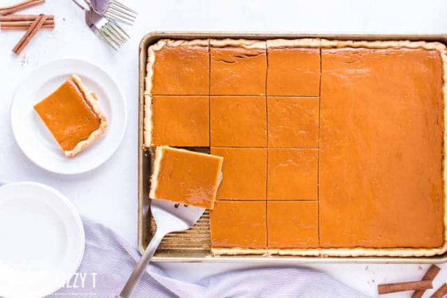 overhead view of pumpkin slab pie with one piece on a spatula