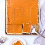 overhead view of pumpkin slab pie with one piece on plate