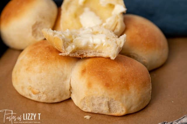 half of a dinner roll on top of other rolls