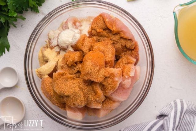 raw chicken with seasoning in a glass bowl