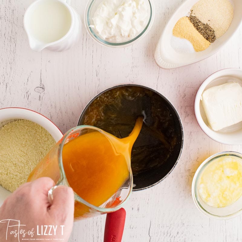 pouring chicken broth into a pan