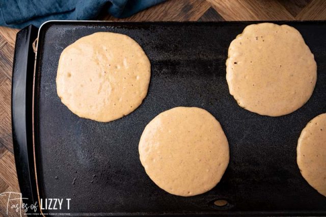 pancakes cooking on a griddle