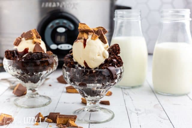 two brownie sundaes on a table with milk