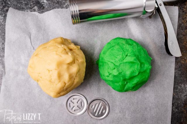 white and green cookie dough on parchment paper with cookie press