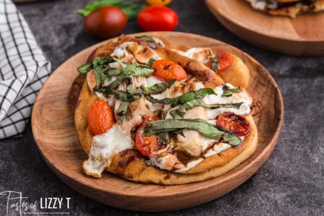 chicken tomato basil pizza on a wooden plate