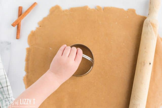 hand using a cookie cutter on rolled dough