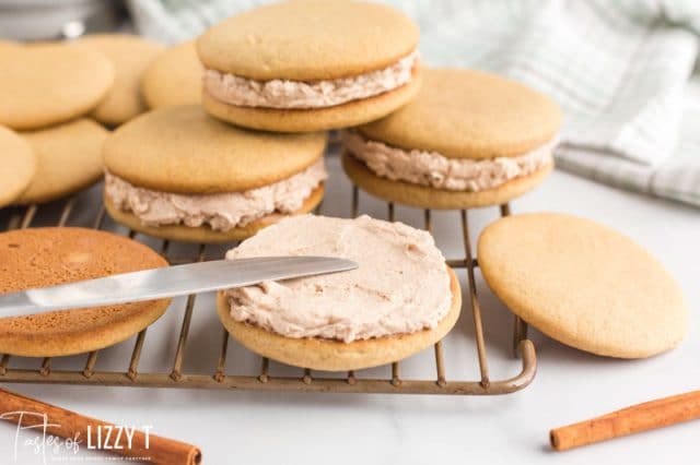 using a knife to spread frosting on cut out cookies