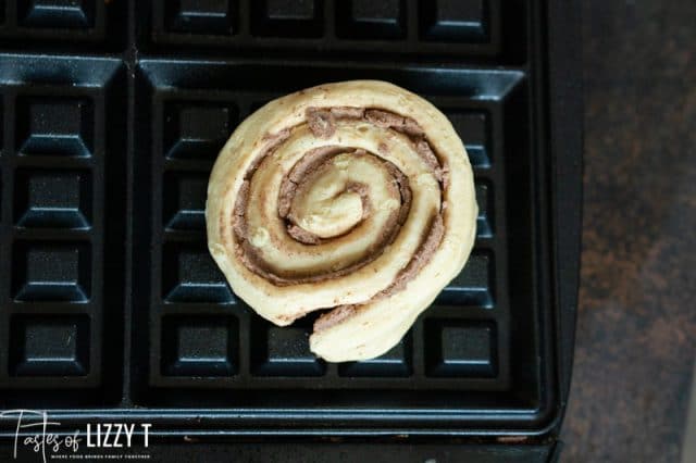 an uncooked cinnamon roll on a waffle iron