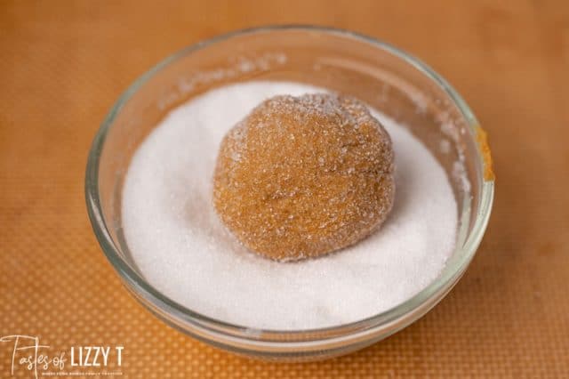 molasses cookie dough ball in a bowl of sugar