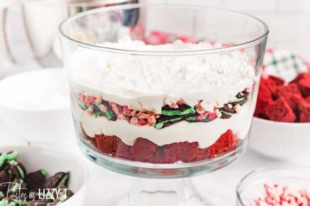 layering cake, cool whip and mint candies in a trifle dish