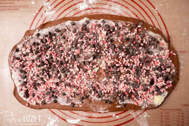 unrolled sweet rolls with toppings on a baking mat