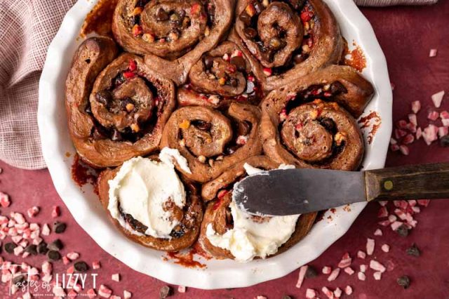 spreading frosting on a pan of sweet rolls