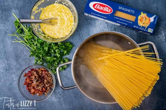 pasta in a pot of water with ingredients on a table
