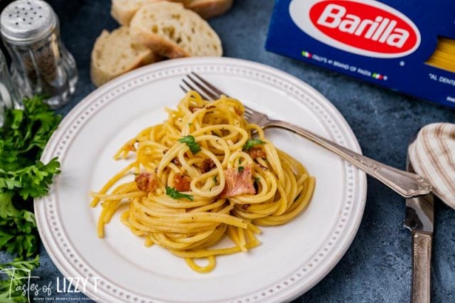 pasta carbonara on a white plate with a fork