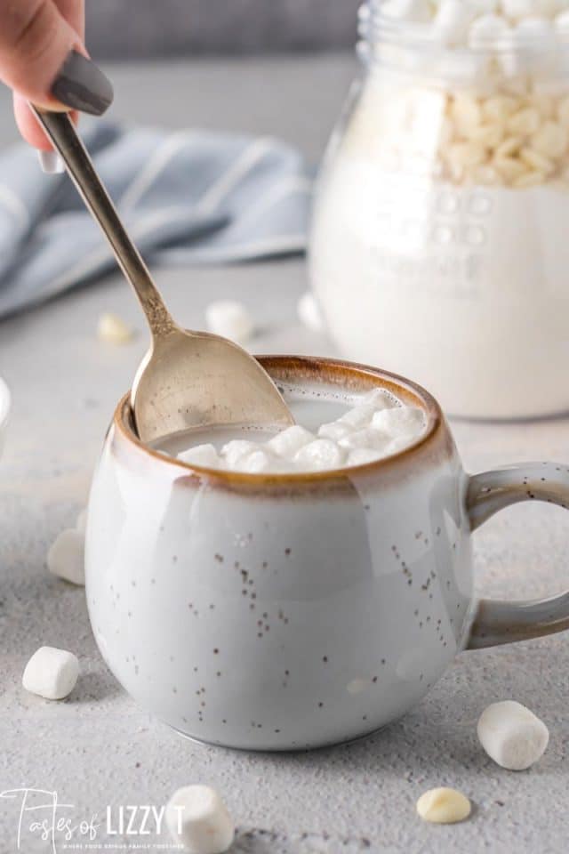 mug of white hot chocolate with spoon stirring