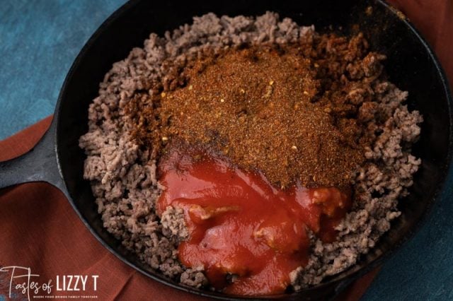 taco meat in a skillet with seasoning and sauce