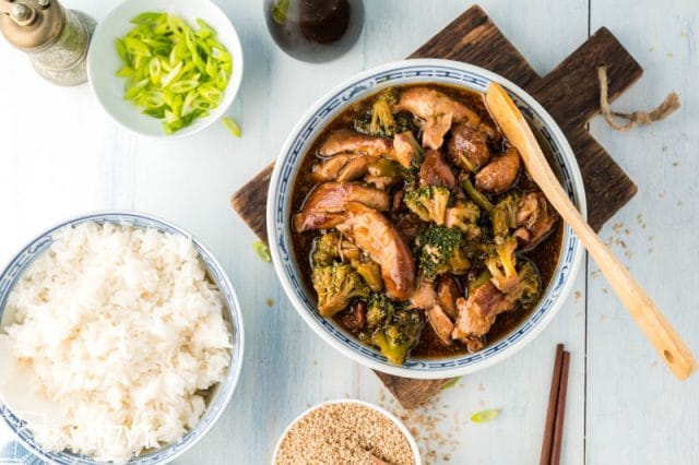 table with bowls of rice, chicken and broccoli