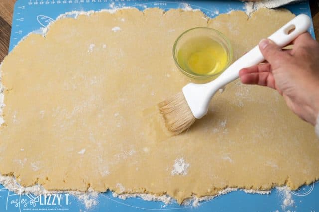 brushing egg whites on rolled cookie dough