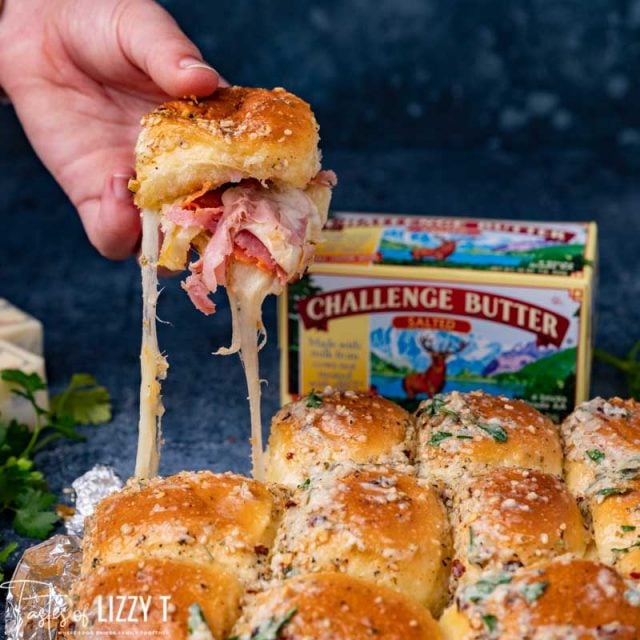 hand holding a pizza slider with stretching cheese