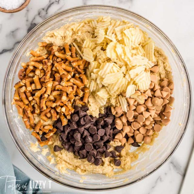 a bowl of cookie dough with chips, pretzels, butterscotch and chocolate chips