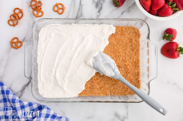 spreading cream cheese over a crust