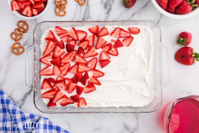 strawberries over cream cheese layer in a pan