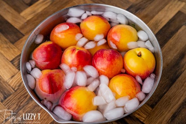 whole peaches in a bowl of ice water