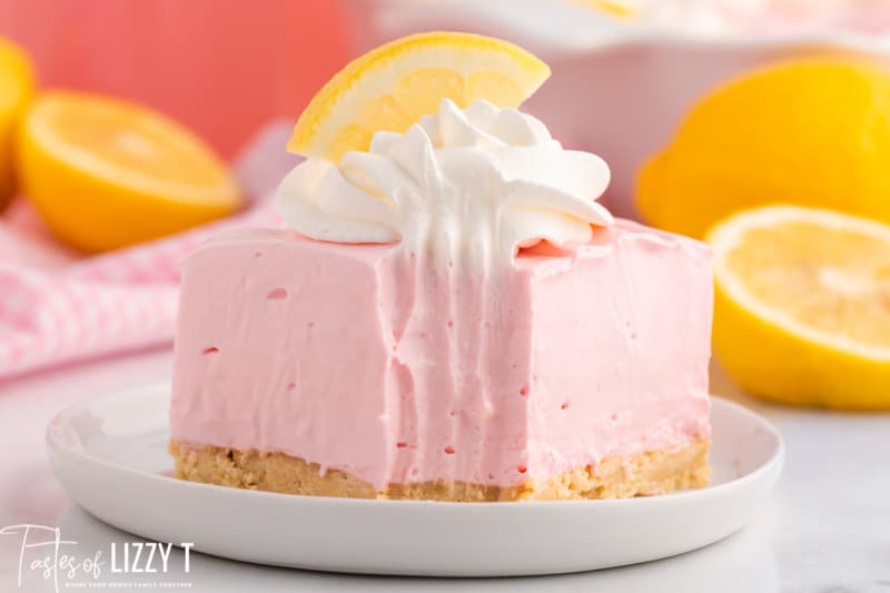 a piece of pink lemonade icebox pie on a plate with a bite out