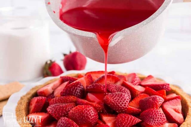 pouring strawberry jello over a pie