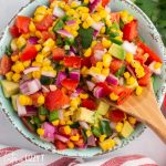 bowl of corn tomato avocado salsa with a spoon