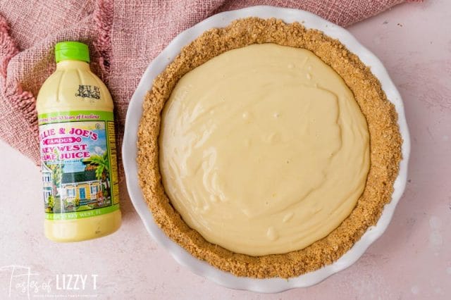 overhead view of an unbaked pie and a bottle of lime juice