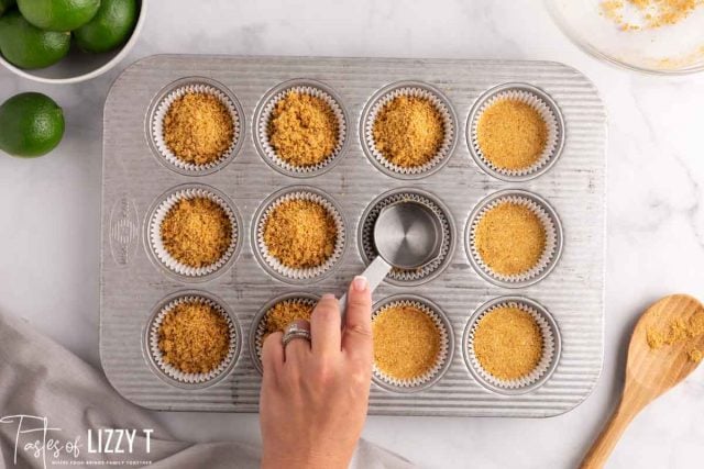pressing cheesecake mix in a muffin tin