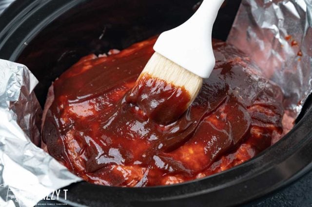 brushing bbq sauce over meatloaf