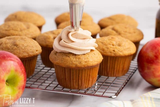 piping a swirl of frosting on a cupcake