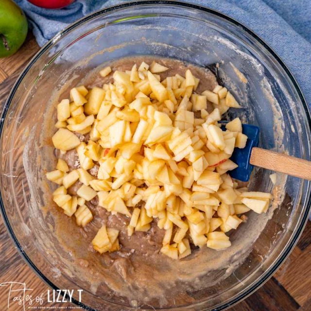 chopped apples over muffin batter in a bowl