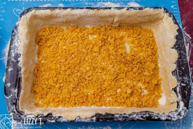 pie dough in a pan with cornflakes over top