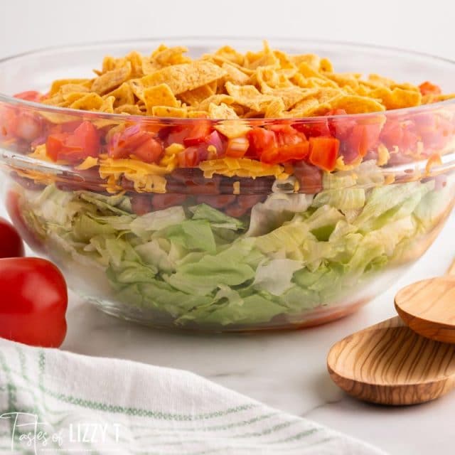 a layered taco salad in a glass bowl