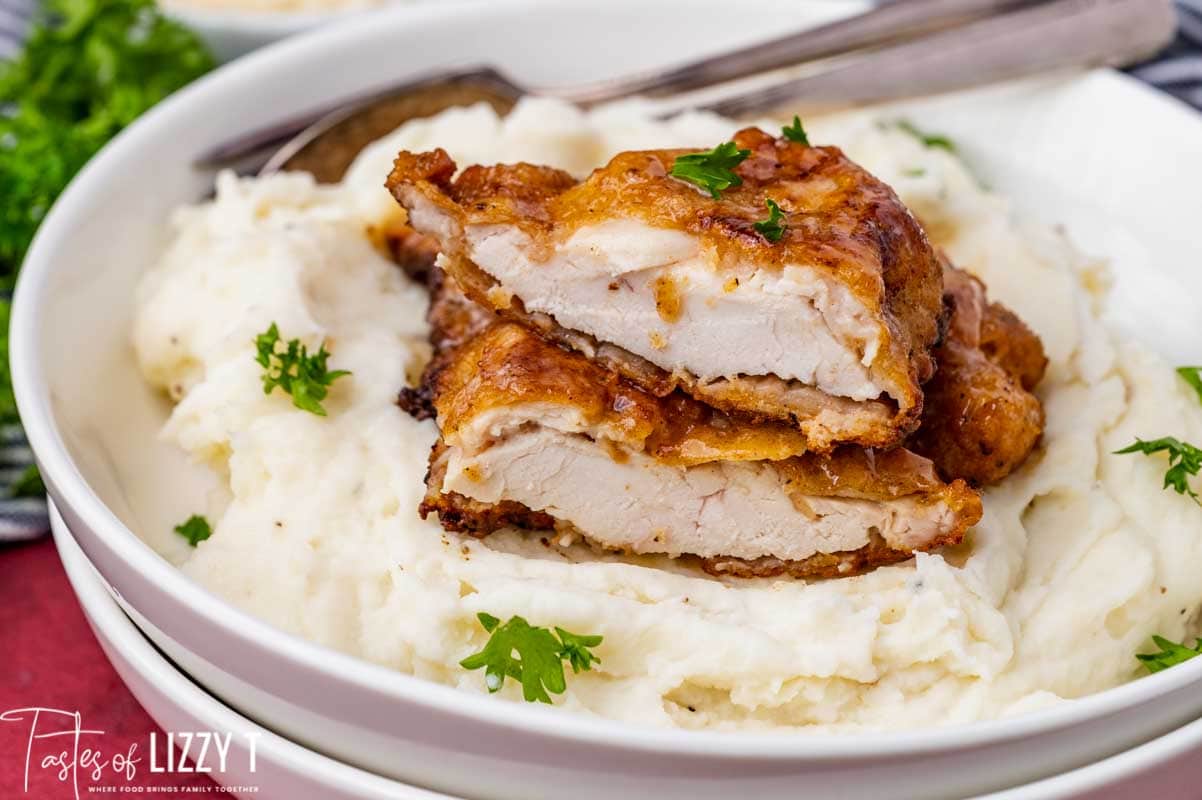 fried chicken breast cut in half over mashed potatoes