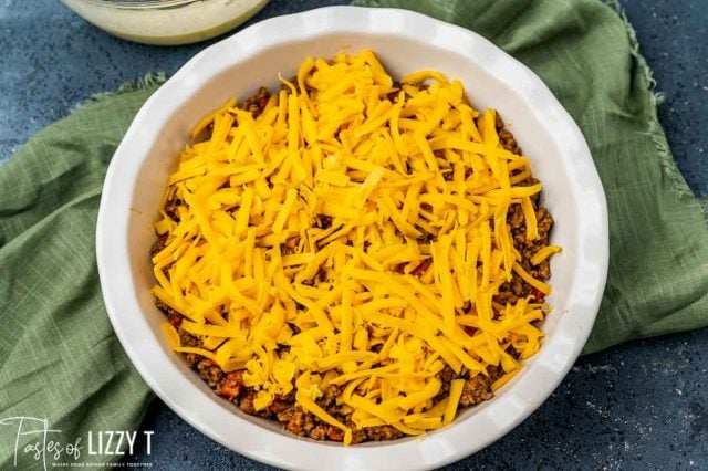 ground beef with cheese over it in a baking pan
